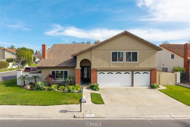 traditional-style house featuring concrete driveway, a front yard, stucco siding, a chimney, and an attached garage