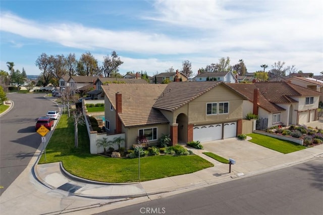 view of front of home with stucco siding, driveway, a tile roof, a residential view, and a front yard