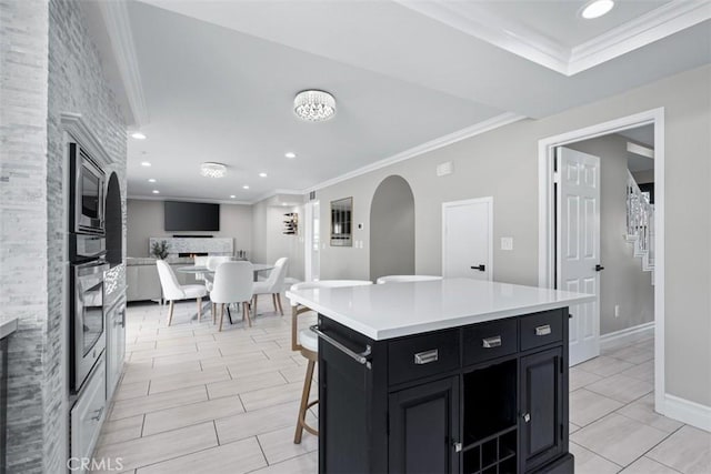 kitchen with crown molding, light countertops, a lit fireplace, appliances with stainless steel finishes, and dark cabinets