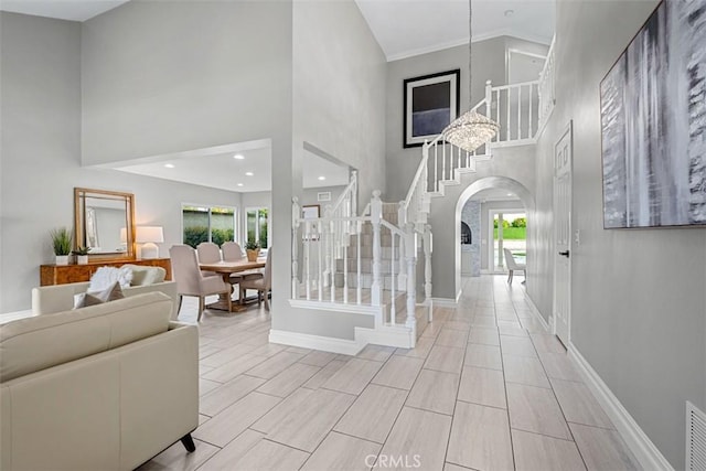 entrance foyer featuring wood finish floors, stairway, arched walkways, a high ceiling, and baseboards