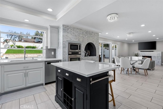 kitchen with dark cabinetry, a warm lit fireplace, a sink, stainless steel appliances, and open floor plan