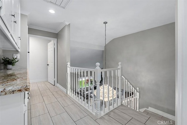 hall with baseboards, an upstairs landing, lofted ceiling, and ornamental molding