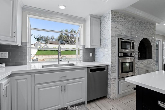 kitchen with a sink, appliances with stainless steel finishes, crown molding, and light countertops