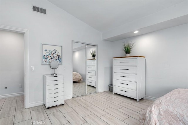 bedroom with a closet, visible vents, baseboards, and lofted ceiling