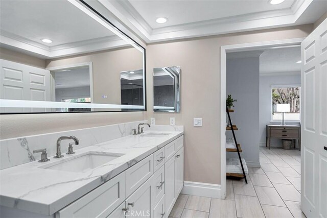 full bath featuring double vanity, baseboards, a tray ceiling, and a sink