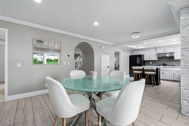 dining area featuring crown molding, wood finish floors, baseboards, recessed lighting, and arched walkways