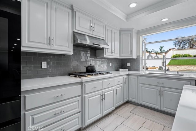 kitchen featuring under cabinet range hood, a sink, light countertops, and stainless steel gas stovetop