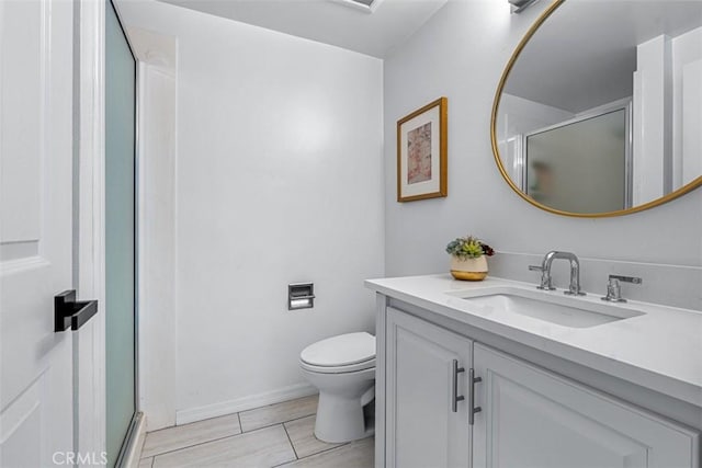 full bath featuring a stall shower, toilet, vanity, and baseboards