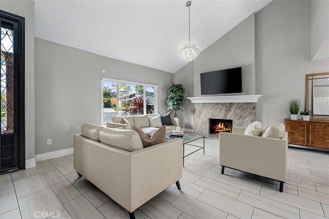 living area featuring baseboards, a high end fireplace, and high vaulted ceiling