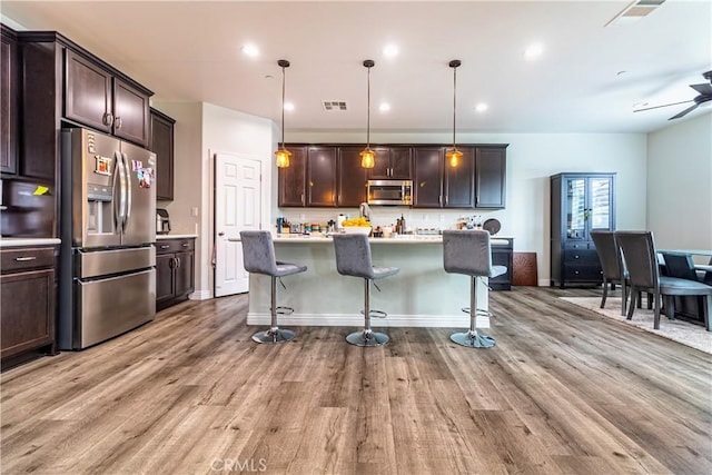 kitchen with dark brown cabinetry, light wood-style floors, visible vents, and appliances with stainless steel finishes