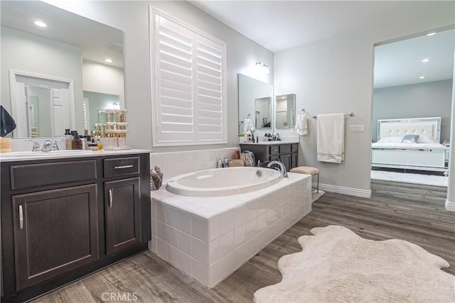 full bathroom featuring a bath, wood finished floors, ensuite bathroom, and a sink