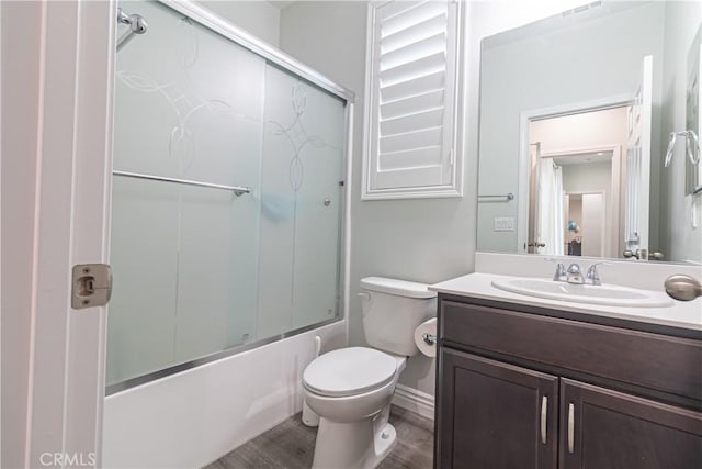 full bath featuring wood finished floors, toilet, vanity, and bath / shower combo with glass door