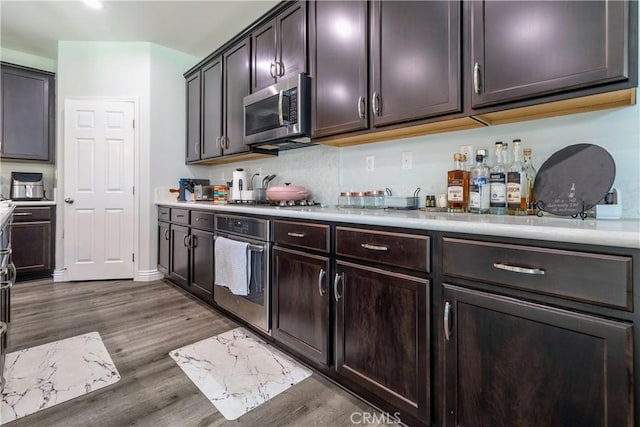 kitchen with dark wood finished floors, light countertops, dark brown cabinets, and stainless steel appliances