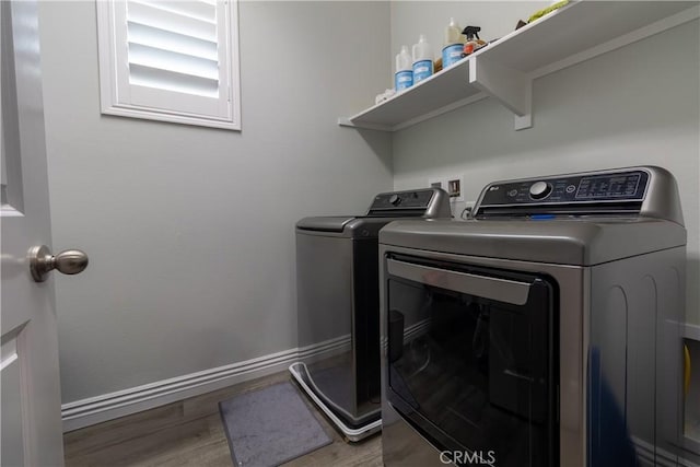 washroom featuring laundry area, wood finished floors, baseboards, and washer and clothes dryer