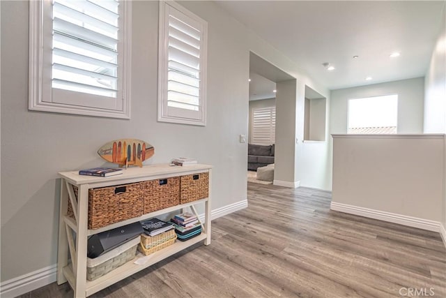 hallway featuring recessed lighting, wood finished floors, and baseboards