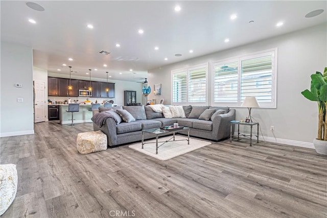 living room featuring recessed lighting, visible vents, baseboards, and light wood-style floors