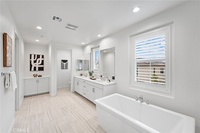 bathroom with vanity, toilet, visible vents, and a freestanding bath