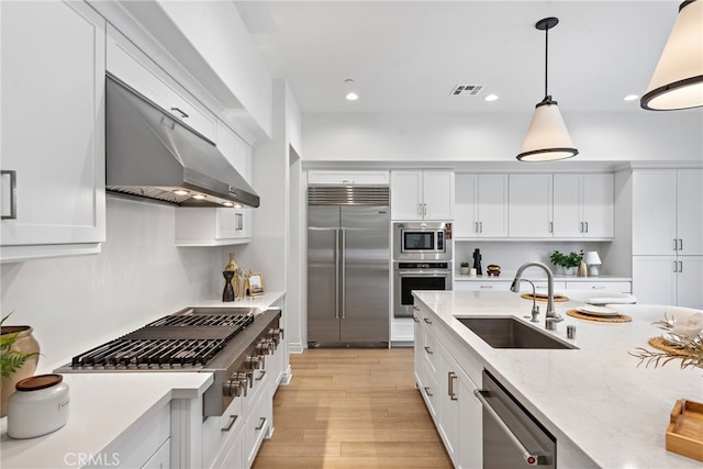 kitchen with visible vents, a sink, under cabinet range hood, built in appliances, and light wood-type flooring