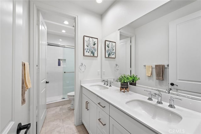 bathroom with double vanity, a shower stall, toilet, and a sink