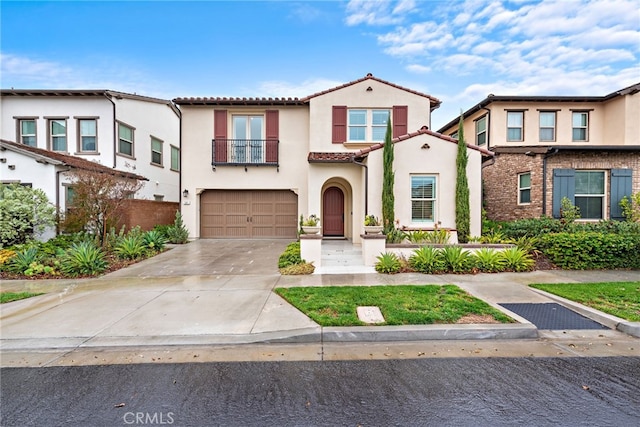 view of front of property featuring a balcony, driveway, an attached garage, stucco siding, and a tile roof