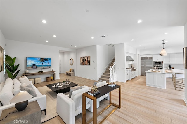 living area with recessed lighting, visible vents, stairs, and light wood finished floors