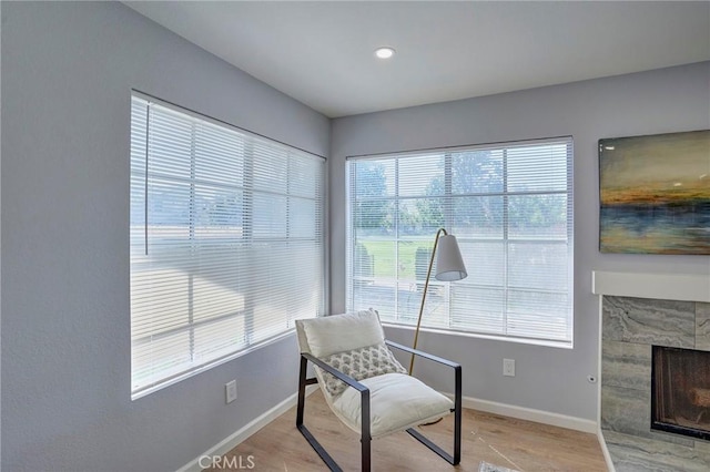 sitting room featuring baseboards, light wood-style flooring, and a fireplace