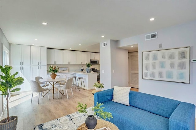 living area featuring recessed lighting, visible vents, and light wood-type flooring