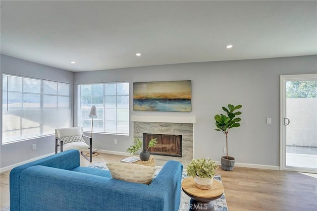 living room with recessed lighting, light wood-style flooring, a fireplace, and baseboards