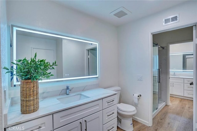 bathroom featuring vanity, wood finished floors, visible vents, a stall shower, and toilet