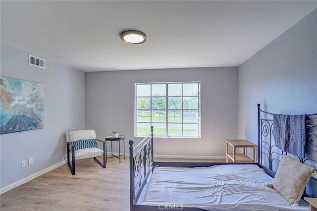 bedroom with wood finished floors, visible vents, and baseboards