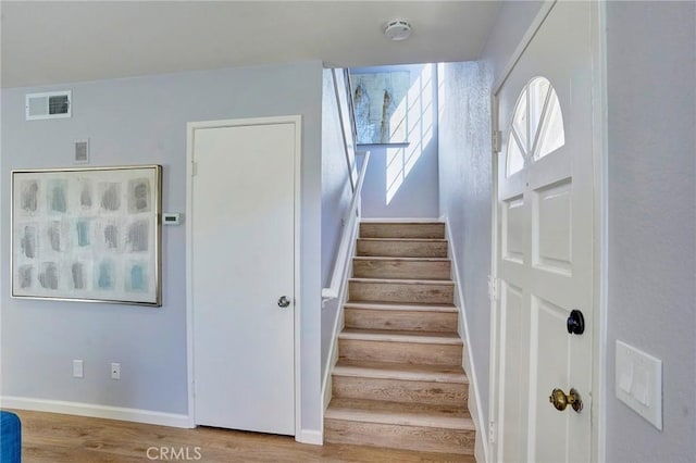 stairway with wood finished floors, visible vents, and baseboards