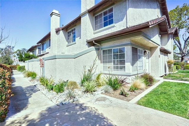 view of side of property with stucco siding and a chimney