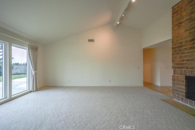 unfurnished living room featuring visible vents, high vaulted ceiling, rail lighting, a fireplace, and light colored carpet