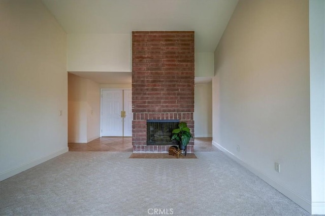 unfurnished living room with a high ceiling, a fireplace, baseboards, and carpet floors