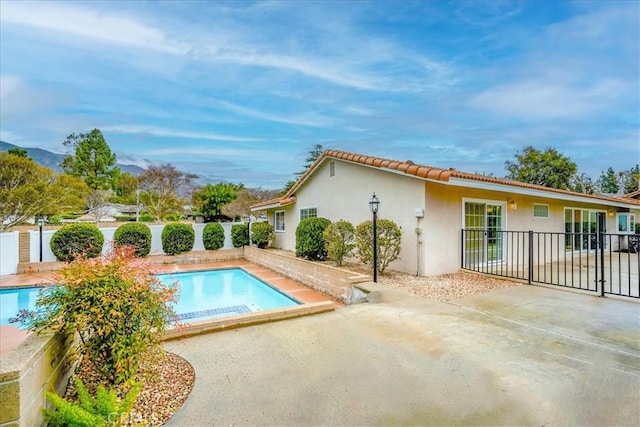 back of property featuring stucco siding, fence, a fenced in pool, and a patio area