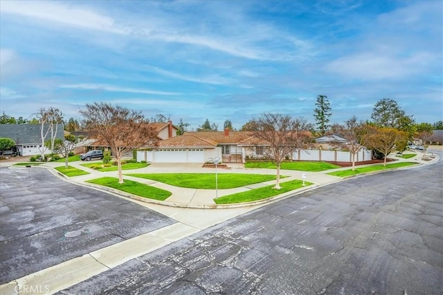 ranch-style house featuring a garage, a residential view, concrete driveway, and a front yard