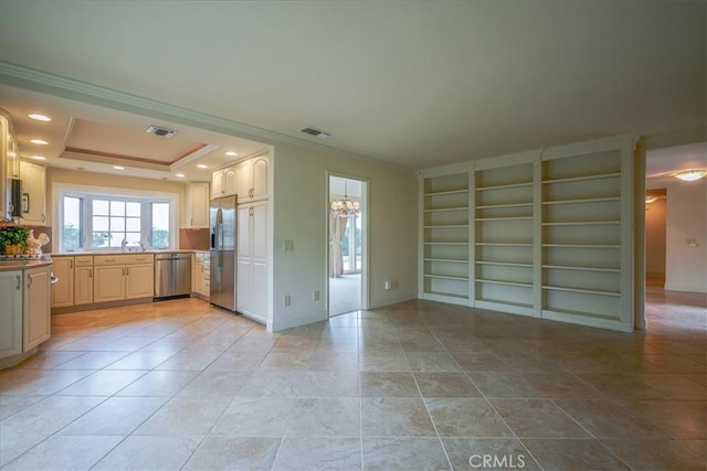 kitchen with visible vents, appliances with stainless steel finishes, an inviting chandelier, crown molding, and a raised ceiling