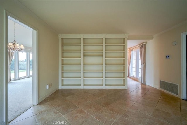 empty room with visible vents, baseboards, a notable chandelier, and ornamental molding