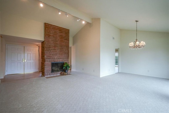 unfurnished living room with carpet flooring, a fireplace, high vaulted ceiling, and an inviting chandelier