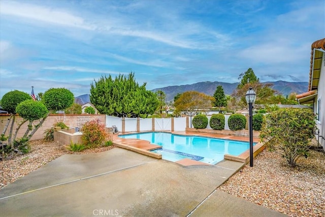 view of pool with a patio, a fenced backyard, a mountain view, and a pool with connected hot tub