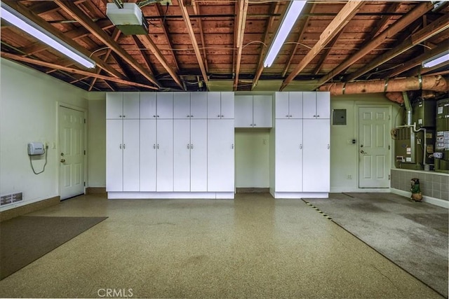 garage with heating unit, visible vents, baseboards, and electric panel