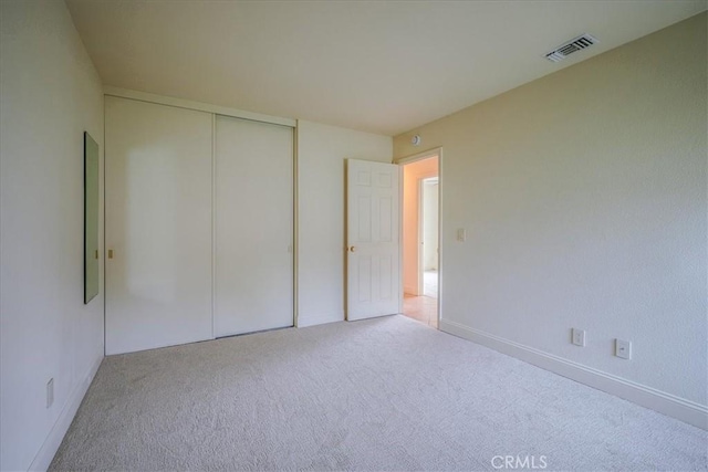 unfurnished bedroom with visible vents, carpet, and a closet