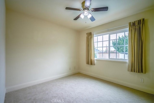 carpeted spare room with a ceiling fan and baseboards