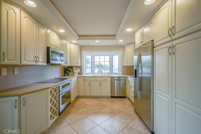 kitchen with light tile patterned floors, a sink, light countertops, appliances with stainless steel finishes, and a raised ceiling