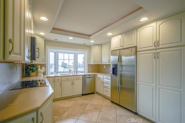 kitchen featuring ornamental molding, light tile patterned floors, stainless steel appliances, a raised ceiling, and a sink