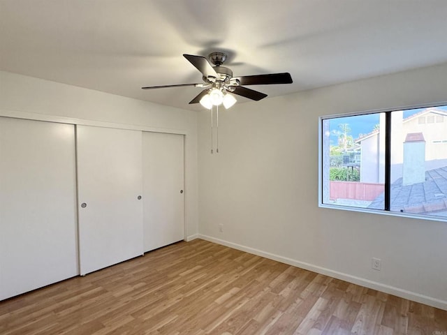 unfurnished bedroom with a closet, baseboards, light wood-style floors, and a ceiling fan