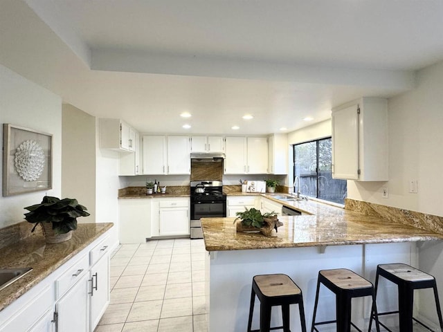 kitchen with range with gas stovetop, recessed lighting, a peninsula, white cabinets, and a sink