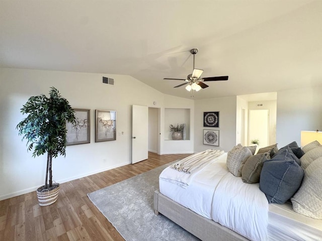 bedroom with visible vents, baseboards, vaulted ceiling, wood finished floors, and a ceiling fan