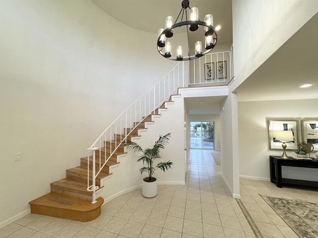 staircase with tile patterned flooring, baseboards, a towering ceiling, and a chandelier