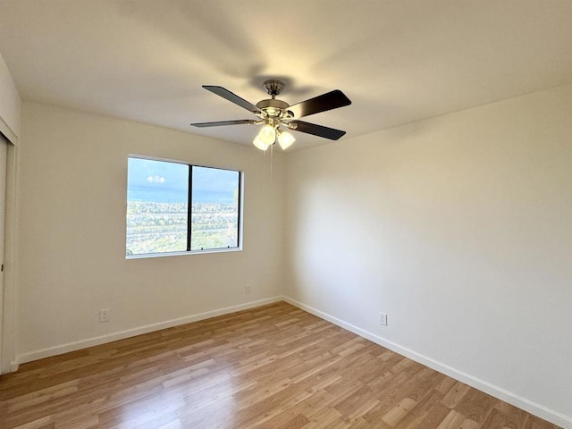 spare room with light wood-type flooring, baseboards, and a ceiling fan